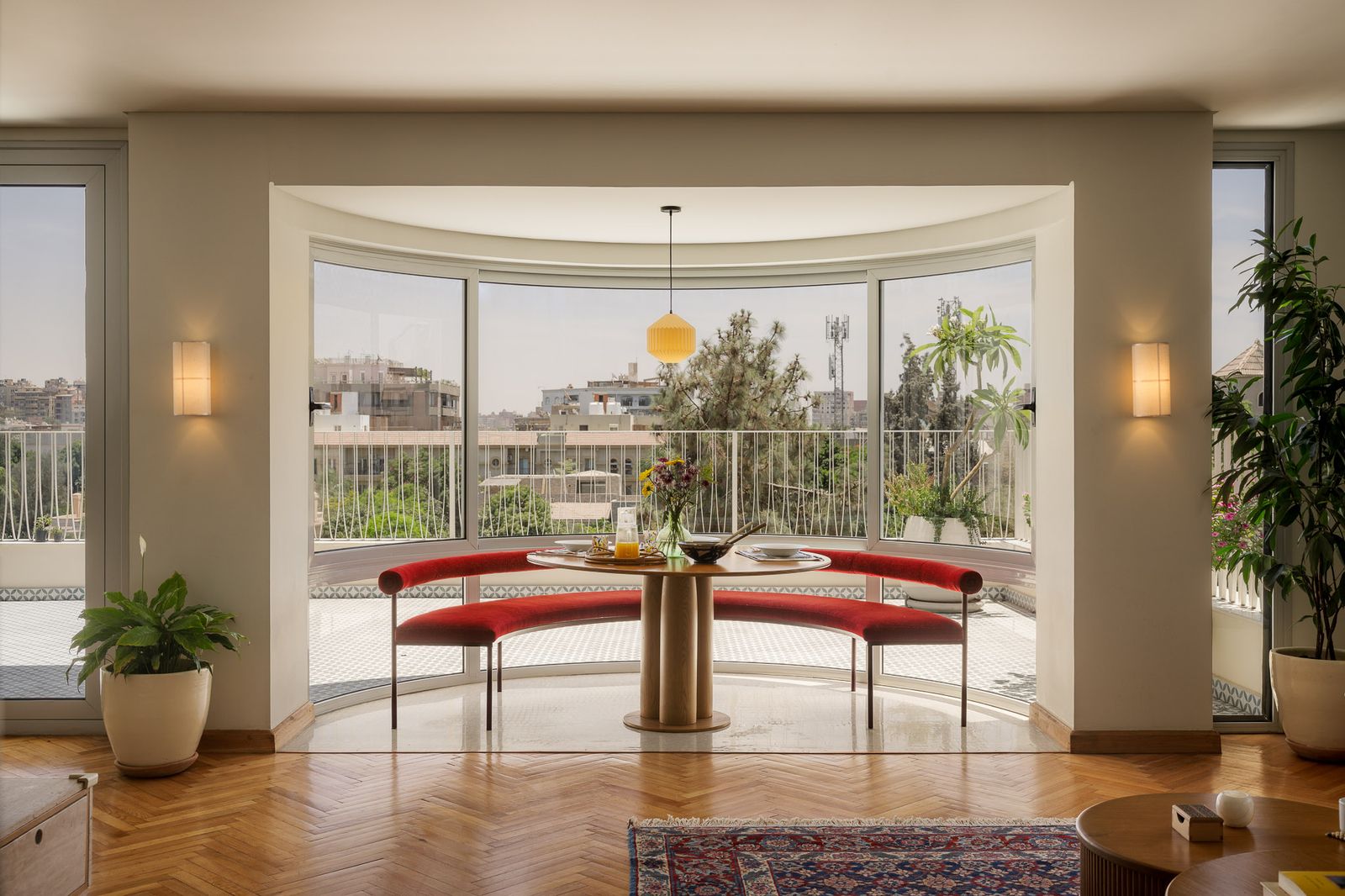 round dining table with red curved bench seating overlooking cairo in Midcentury Apartment in Cairo Deftly Mixes Old and...